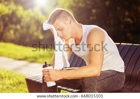 Exhausted male after exercise drinking water and wiping sweat with towel.Tired man resting from sport training
Image is intentionally toned.