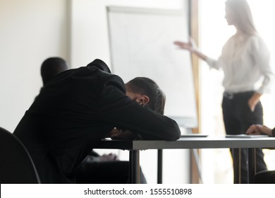 Exhausted male employee fall asleep lying at office desk during team training or meeting, tired man worker feel fatigue having sleep deprivation, suffer from lack of sleep take nap at briefing - Powered by Shutterstock