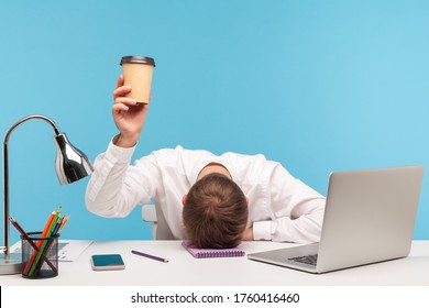 Exhausted male employee feeling fatigue lying on table and raising coffee cup, lack of energy in morning office, tired of stress problems sleeping at workplace, overwork concept. indoor studio shot