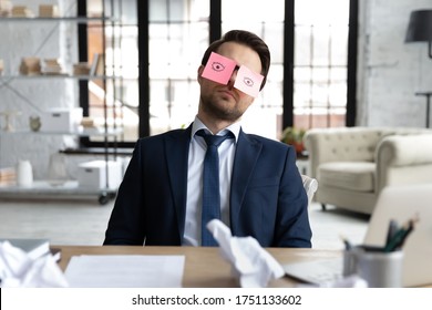 Exhausted male employee sit at desk with stickers on eyes fall asleep nap at workplace, tired businessman or boss sleeping in office, overwhelmed with work, feel fatigue exhaustion, overwork concept