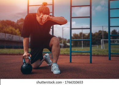 Exhausted Man Athlete Taking Break Between Exercising With Kettlebell Outdoor