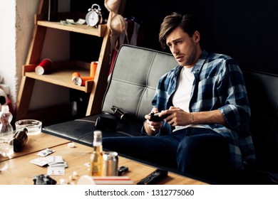 Exhausted Man Playing Video Game In Messy Living Room