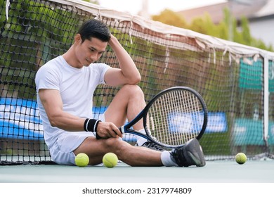 Exhausted man tennis player sitting on the court looking disappointed after practice. - Powered by Shutterstock