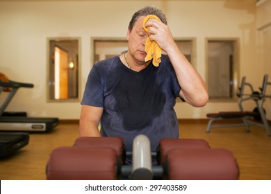 Exhausted Mature Man Wiping Sweat With A Towel After Intensive Training In The Gym