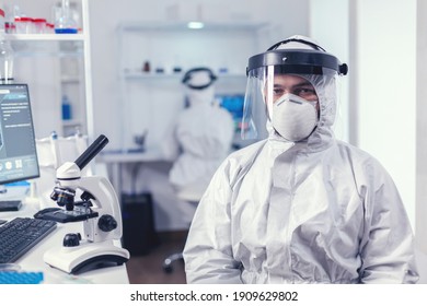 Exhausted medic sitting at workplace wearing ppe suit with visor during covid19 outbreak. Overworked researcher dressed in protective suit against invection with coronavirus during global epidemic. - Shutterstock ID 1909629802