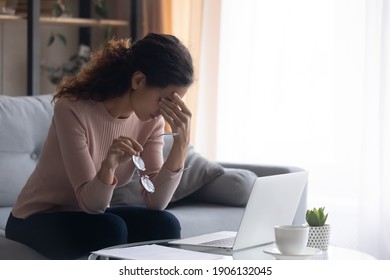 Exhausted millennial caucasian woman taking off eyeglasses, suffering from dry eyes syndrome from long computer overwork at home. Tired young female freelancer having problem with blurred eyesight.