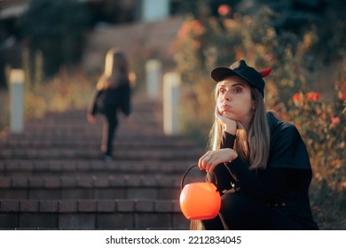 
Exhausted Mom Holding Pumpkin Candy Bucket Taking A Break. Stressed Mother Going To A Party With Her Toddler Child
