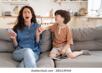 Exhausted Mummy Helpless Scream Stressed With Disobedient Preschool Son Distracting Her From Surfing Web Or Online Shopping In Smartphone App. Stubborn Misconduct Kid Annoy Desperate Tired Mom At Home