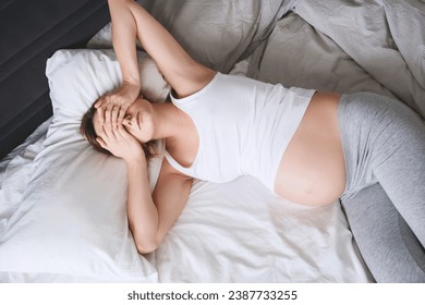 Exhausted pregnant woman lying in bed. Prenatal woman getting a contraction, suffering from tiredness, insomnia, pain. Expectant mother feeling unwell or sick during pregnancy. - Powered by Shutterstock