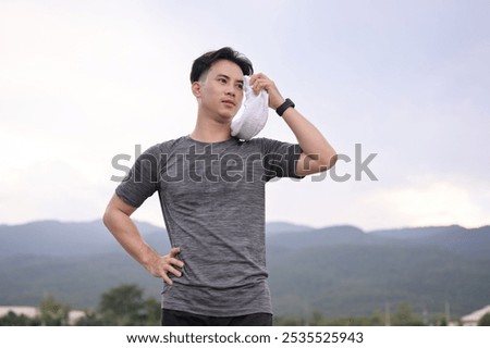Exhausted runner cooling down after outdoor workout and using towel wipe sweat