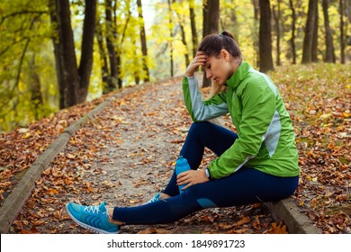 Exhausted Runner Having Rest After Workout In Autumn Park. Tired Woman Holding Water Bottle. Sportive Lifestyle