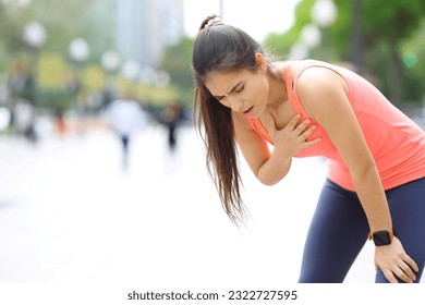 Exhausted runner touching chest breathing in the street