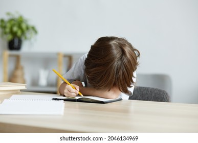 Exhausted School Kid Is Tired From Homework And Learning And Is Lying On The Desk. Difficulties In Children's Learning And Problems With School Tests And Exercises. Overwork And Stress In Preschool.