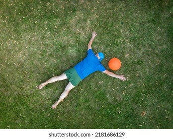 Exhausted Senior Man Lying Down On A Grass And Resting After Heavy Slam Ball Workout, View From Above