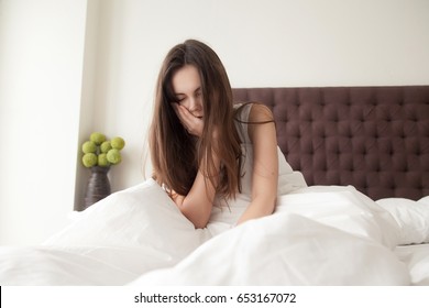 Exhausted Sleepy Young Woman Sitting In Bed With Messy Hair, Feeling Drowsy After Wake Up Too Early In Morning, Sleepless Night. Tired Female Teenager Suffering Of Insomnia, Lack Of Sleep Or Toothache