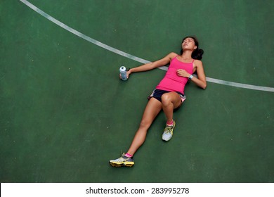 Exhausted Sporty Woman Runner Laying On Basketball Court After Fitness Running Workout Outdoors