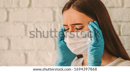 Exhausted stressed girl female doctor in protective mask on face and medical gloves suffering from headache. Tired sick woman in medical face mask and gloves. Coronavirus COVID-19 symptoms. High fever