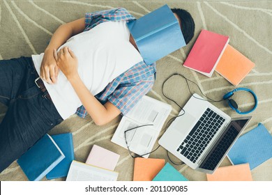 Exhausted student fall asleep with a textbook on his face - Powered by Shutterstock