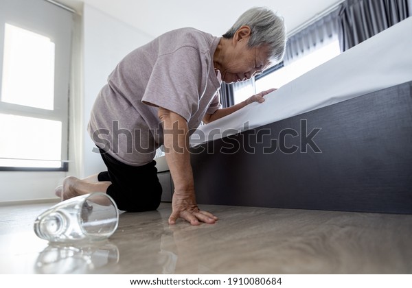 Exhausted tired asian old elderly closed her eyes\
having high blood pressure headache,fatigue,vertigo,feel\
dizzy,faint,fell on the floor,senior woman trying to help herself\
stand up after falling\
down