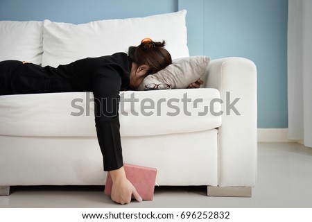 Exhausted, Tired, Lazy, sleepy Asian Business woman in black suit lying on white sofa with blue wall and copy space. Stress from overtime working concept. Foto stock © 