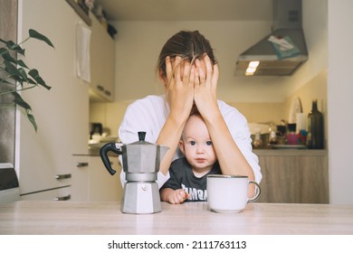 Exhausted Woman With Baby Is Sitting With Coffee In Kitchen. Modern Young Tired Mom And Little Child After Sleepless Night. Life Of Working Mother With Baby. Postpartum Depression On Maternity Leave.