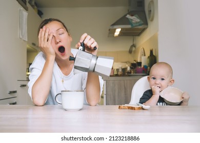 Exhausted Woman With Baby Is Sitting With Coffee In Kitchen. Modern Young Tired Mom And Little Child After Sleepless Night. Life Of Working Mother With Baby. Postpartum Depression On Maternity Leave.