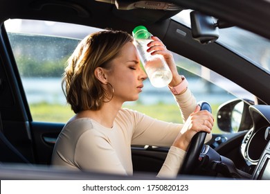 Exhausted woman driver feeling headache, sitting inside her car, applies a bottle of water to his forehead, hot weather. Stop after driving car in traffic jam. Blood pressure