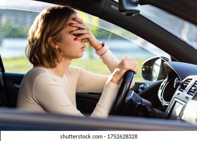 Exhausted woman driver feeling headache, sitting inside her car, keeping hand to head and feeling anxiety. Stop after driving car in traffic jam.Blood pressure