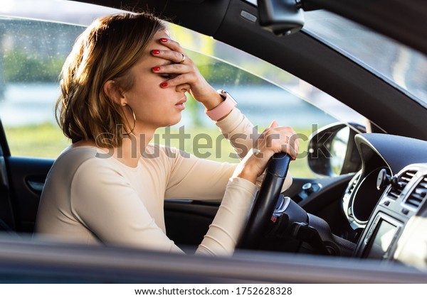Exhausted woman driver feeling\
headache, sitting inside her car, keeping hand to head and feeling\
anxiety. Stop after driving car in traffic jam.Blood\
pressure