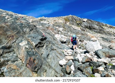 Exhausted woman hiking uphill on the way to Hoher Sonnblick in High Tauern mountains in Carinthia, Salzburg, Austria, Europe, Alps. Ascent in Hohe Tauern National Park. Freedom concept. Path mark