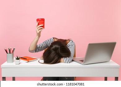 Exhausted woman laid her head down on the table holding cup of coffee or tea sit, work at white desk with pc laptop isolated on pastel pink background. Achievement business career concept. Copy space - Shutterstock ID 1181047081