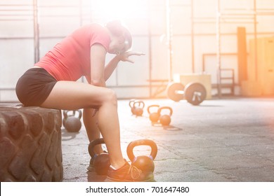 Exhausted Woman Sitting On Tire In Crossfit Gym