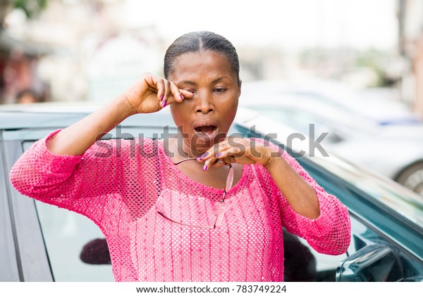 exhausted
woman standing in front of her car and
yawning
