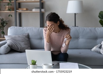 Exhausted woman taking off glasses, suffering from eye strain, dry eye syndrome, massaging eyelids, tired stressed female sitting on couch, businesswoman feeling fatigue after long laptop use - Shutterstock ID 1755923219