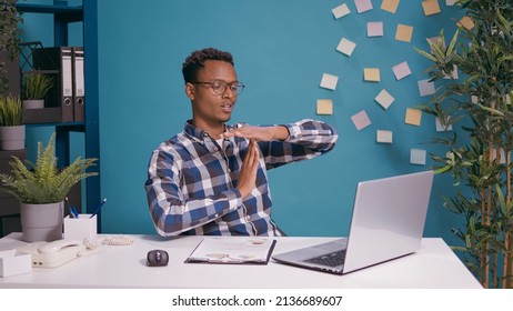 Exhausted worker doing timeout sign with hands in front of laptop screen, showing t shape symbol to take break from business work. Tired person hoping for pause after being overworked.