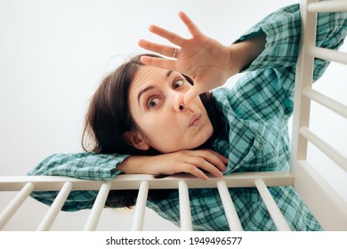 Exhausted Yawning Mother Attending Baby in Crib. Tired mom trying to calm her baby crying. Overworked parent in nursery comforting newborn
