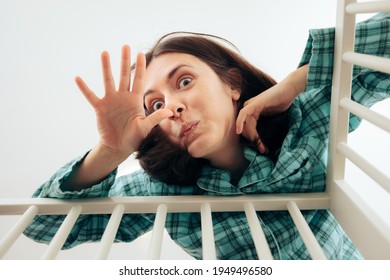 Exhausted Yawning Mother Attending Baby In Crib. Tired Mom Trying To Calm Her Baby Crying. Overworked Parent In Nursery Comforting Newborn