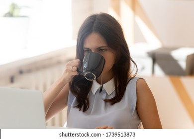 Exhausted young female employee drink tea overwhelmed with computer work, tired sick woman worker feel fatigue exhaustion at workplace, lack motivation in office, overwork, exhaustion concept