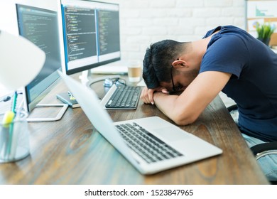 Exhausted young male software developer sleeping by technology while leaning on desk - Powered by Shutterstock