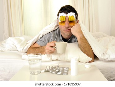 Exhausted Young Man In Bed With Coffee, Water And Tablets Suffering Hangover And Headache