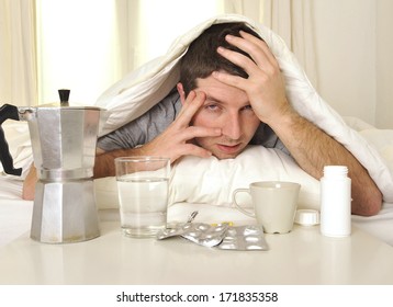 Exhausted Young Man In Bed With Coffee, Water And Tablets Suffering Hangover And Headache