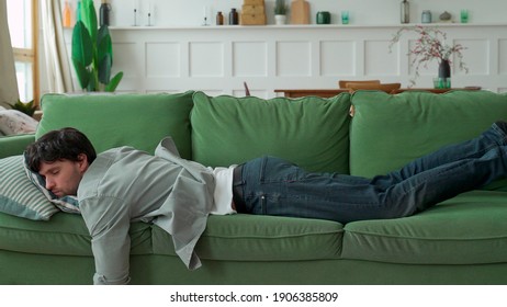 Exhausted young man came home after work flopped down on sofa