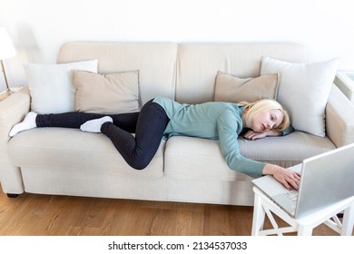 Exhausted young woman lying on sofa, using laptop, too tired or bored of online work at home, free space. Workaholism, chronic fatigue, overworking on remote job concept - Shutterstock ID 2134537033