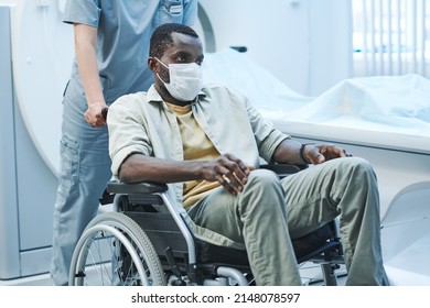 Exhauster Black Coronavirus Patient In Facial Mask Sitting On Wheelchair Pushed By Nurse After MRI