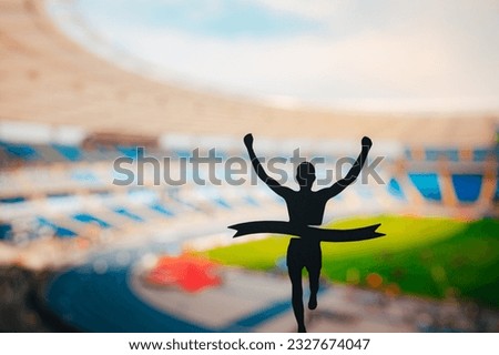 Exhilarating Finish: Silhouetted Runner Claims Victory at Modern Athletics Stadium. Edit Space, Track and Field Competition Photo.