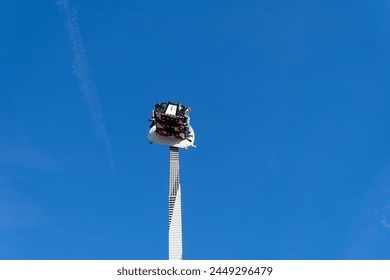 An exhilarating free-falling rotating tower ride, soaring through the clear sky, offering breathtaking views and a rush of excitement at a country fair in Italy