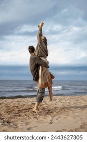 An exhilarating moment of a woman being lifted in the air by a man on the beach, both exuding happiness and freedom, a perfect capture of joyous couple goals. High quality photo