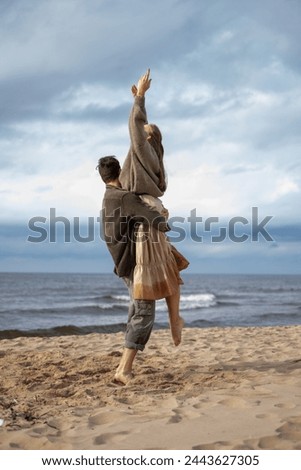 An exhilarating moment of a woman being lifted in the air by a man on the beach, both exuding happiness and freedom, a perfect capture of joyous couple goals. High quality photo