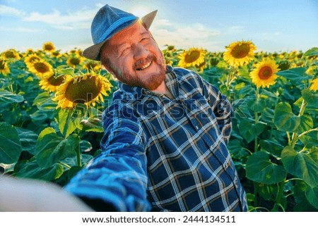 exhilaration smiling senior handsome man farmer visiting sunflower field and taking photo selfie