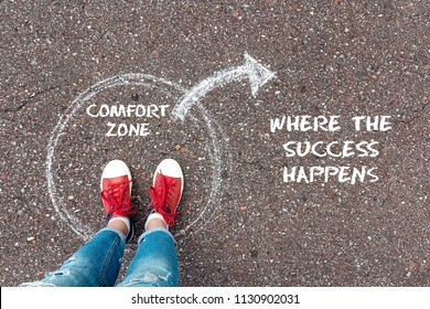 Exit from the comfort zone concept. Feet  in red sneakers standing inside circle comfort zone and outward arrow chalky on the asphalt. - Shutterstock ID 1130902031